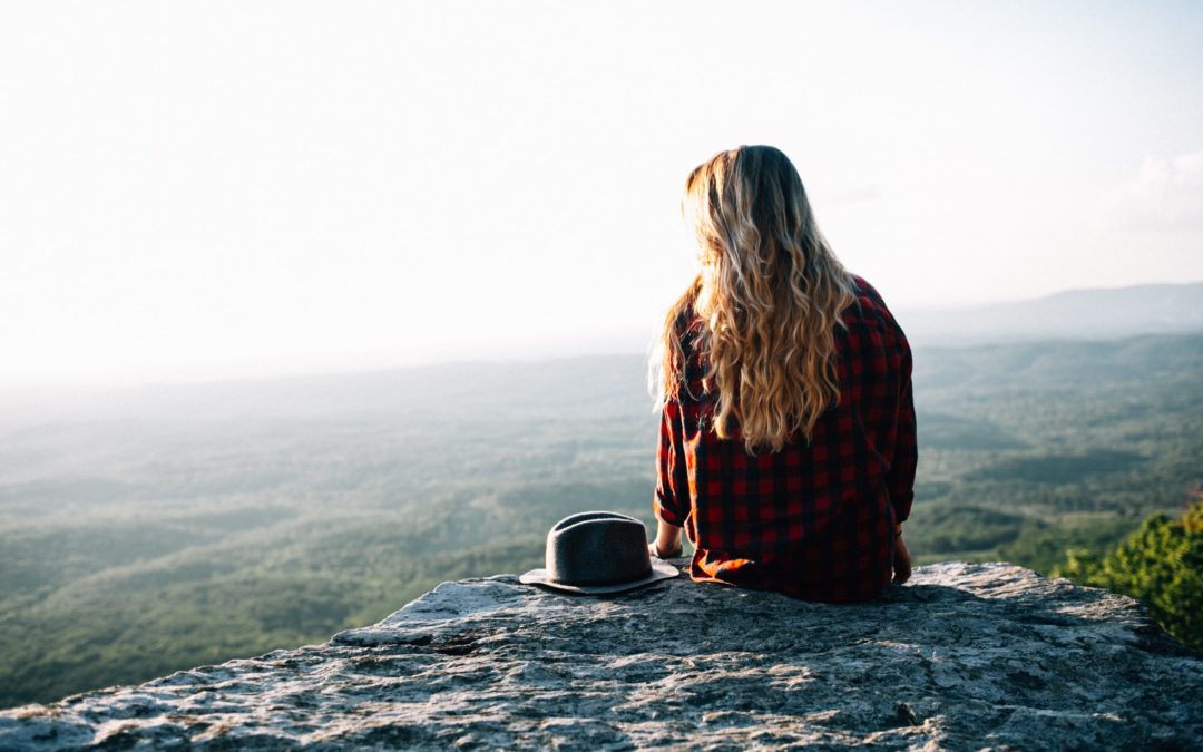Young woman sitting on mountain top balancing estrogen